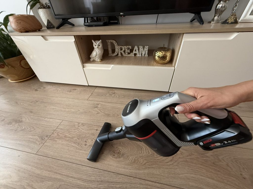 Vacuuming the floor in front of a cabinet in a living room