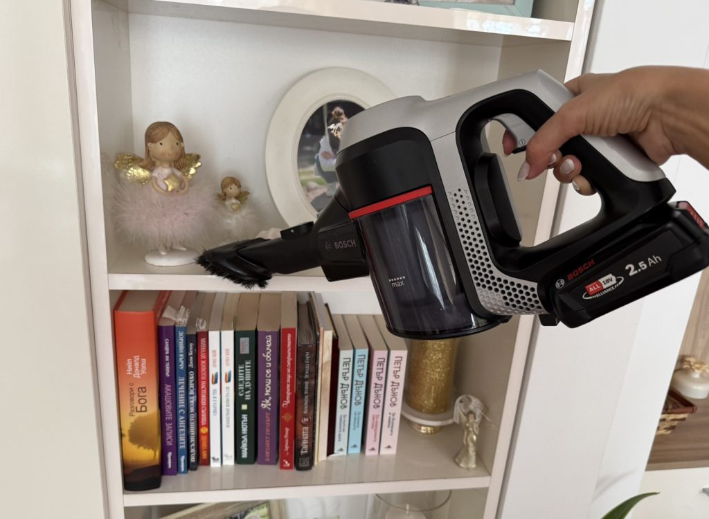 Dusting an accessible shelf with a vacuum cleaner brush